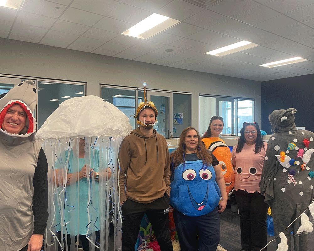 Coworkers in ocean-themed costumes, including a shark, a jellyfish and Dory.